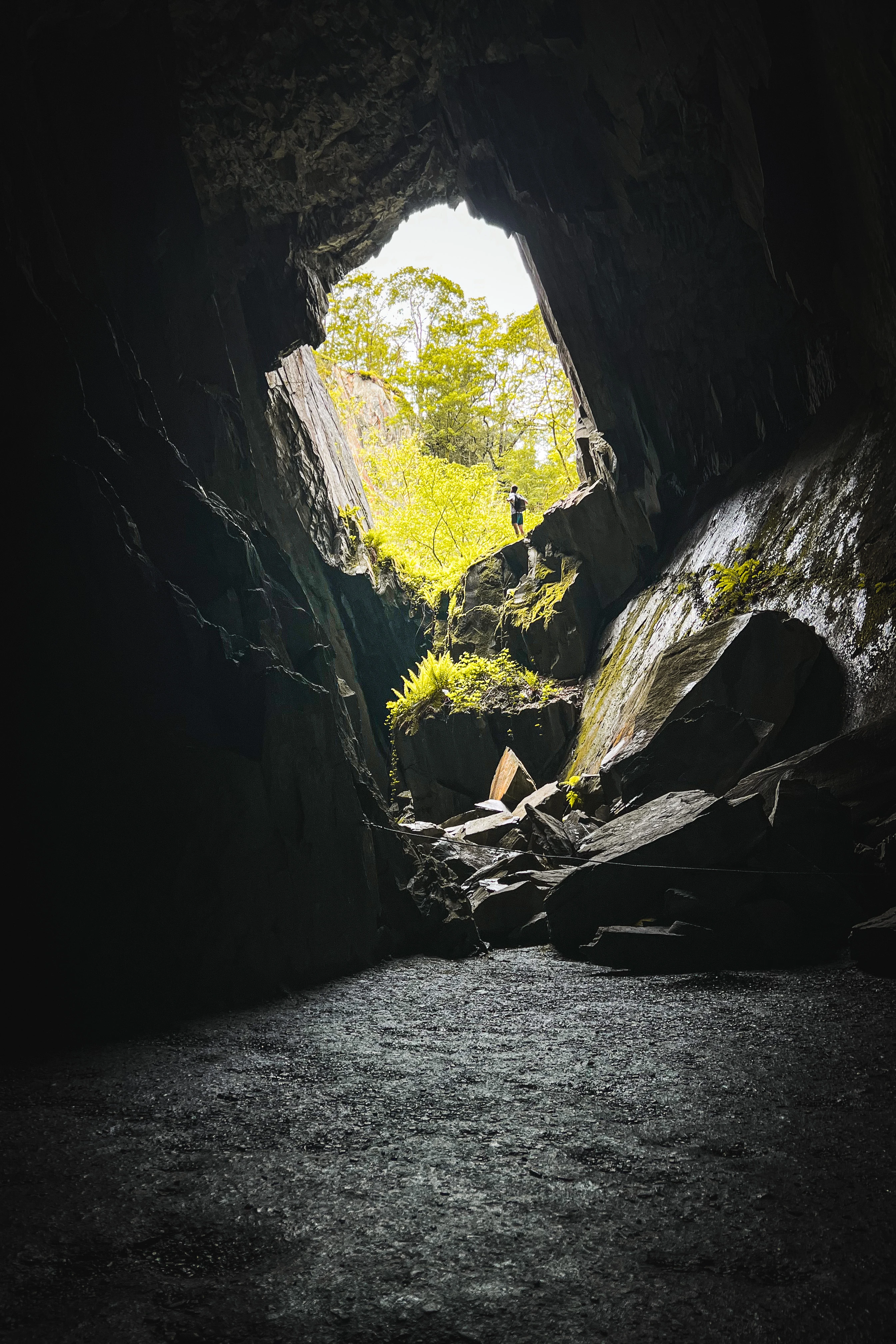 Looking up through a quarry chasm toward a hiker at the opening